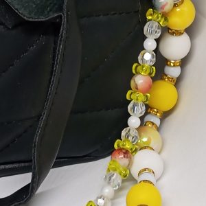 Close-up of white daisy charm on yellow beaded bag dangle