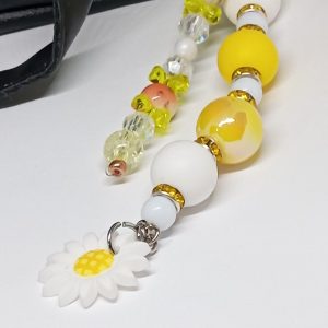 Close-up of white daisy charm on yellow beaded bag dangle